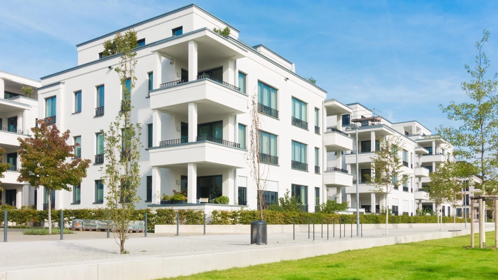 Moderne weiße Wohnanlage mit Balkonen und begrünter Außenanlage